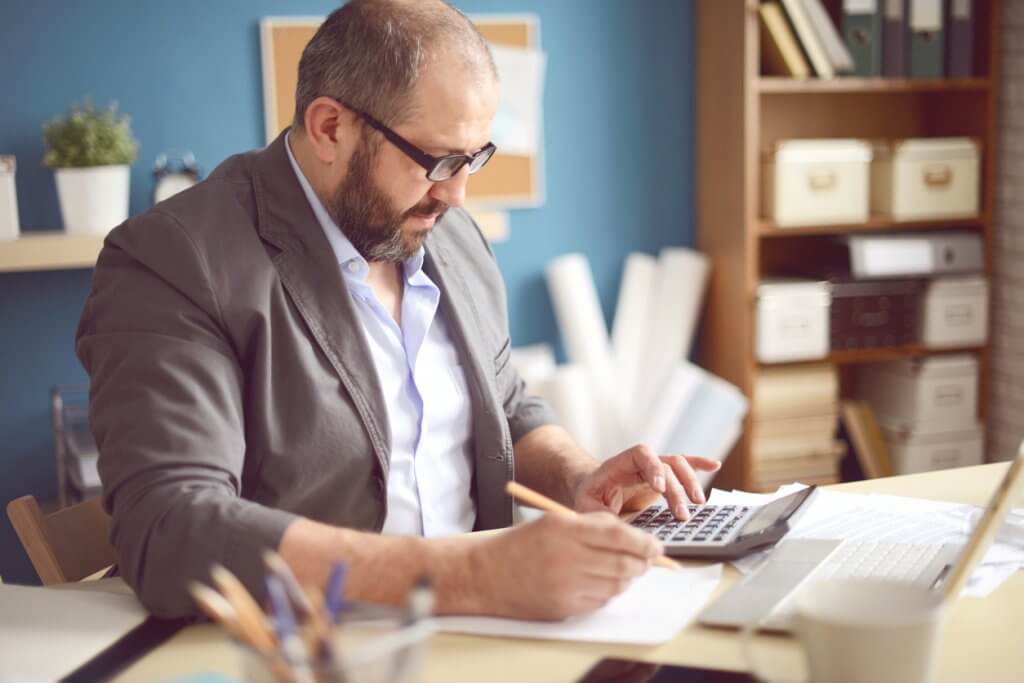 adult man creating business budget using calculator